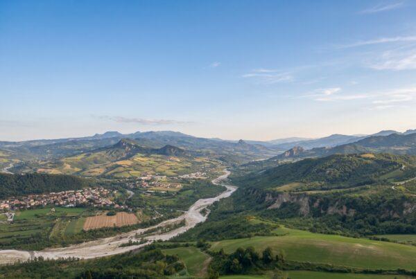 Scenic view of the rolling green hills and vineyards in Rimini, Emilia-Romagna, a prime location for buying property in Italy.